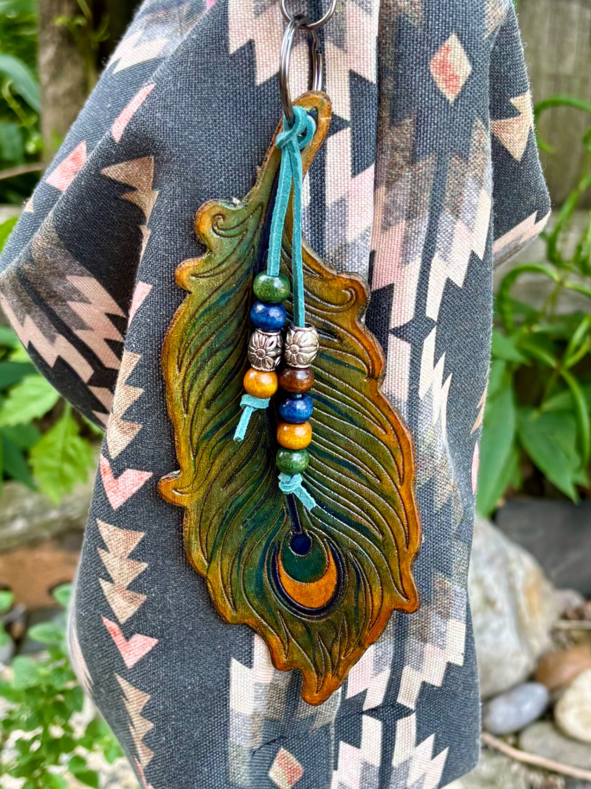 Peacock feather leather bag charm clipped to a gunmetal swivel hook, bead detail