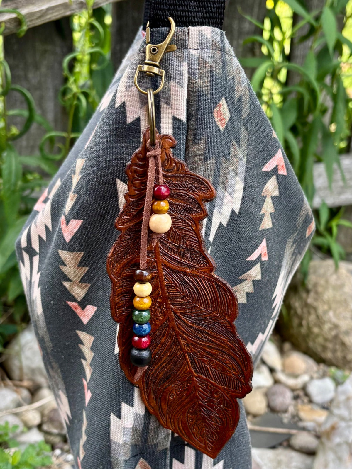 Close-up of hand-tooled leather feather texture and bronze swivel clasp