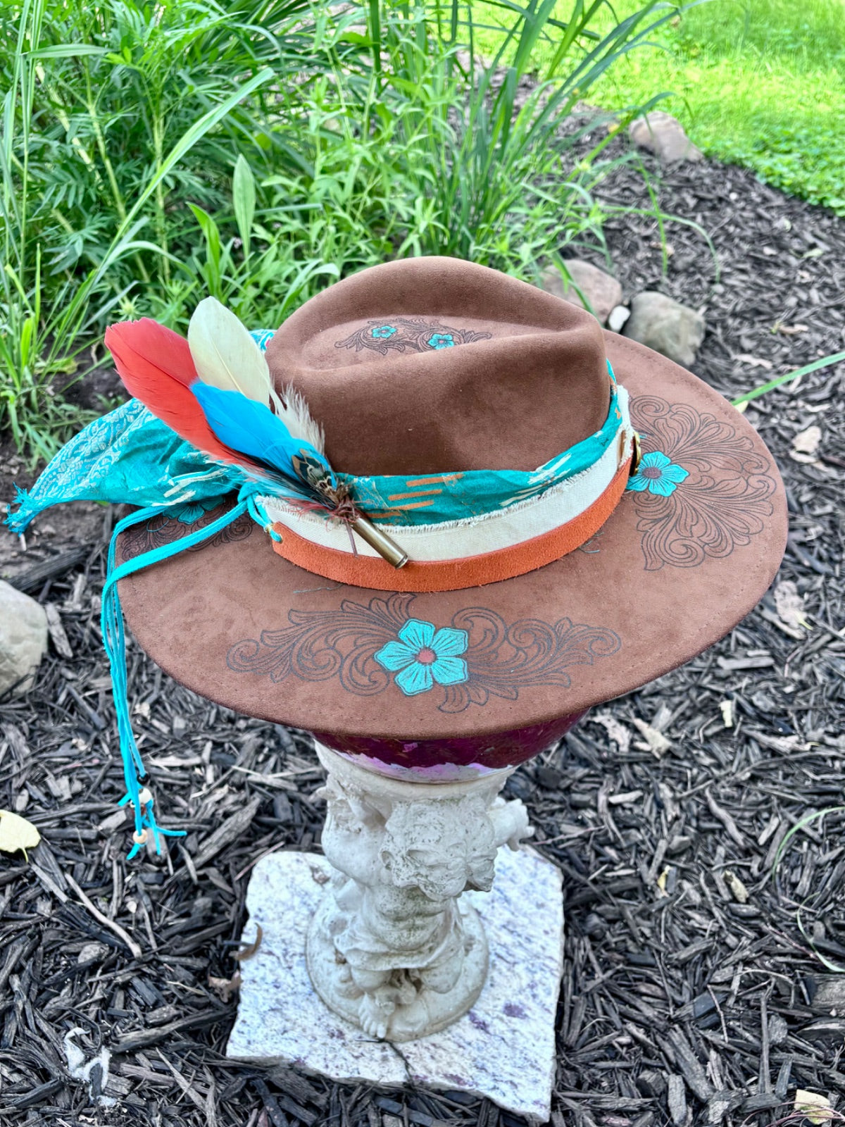 Close-up of hand-painted turquoise flower design on brown suede rancher hat