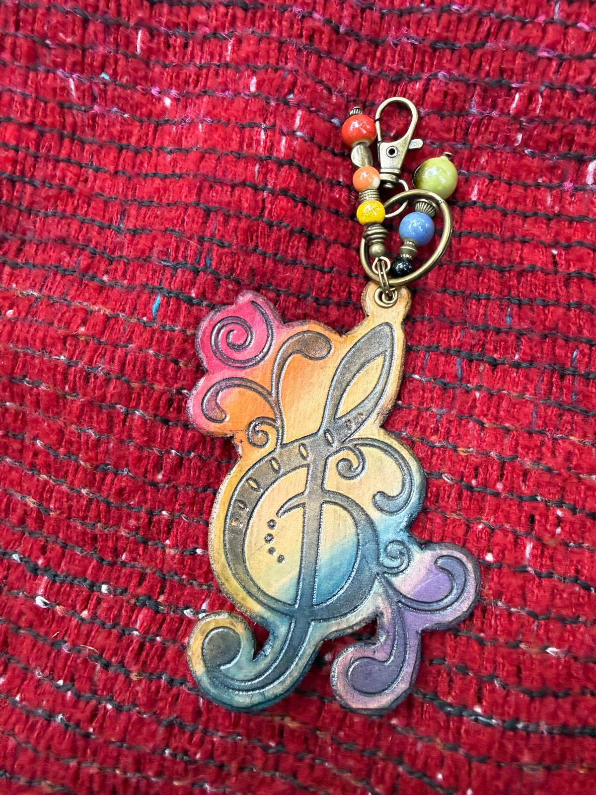 Hand-tooled leather treble clef bag charm in rainbow ombre, close up