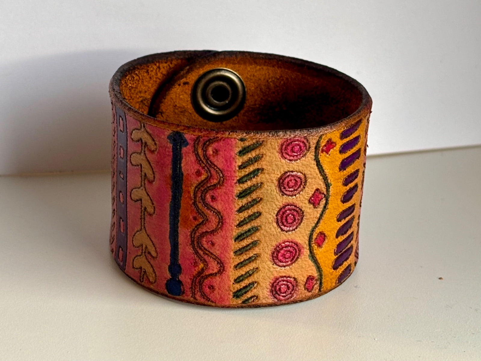 Wide hand-painted tribal leather cuff bracelet in pink, orange, and purple by Angie Meyers Designs
