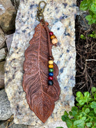 Tooled brown leather feather bag charm with rainbow wood beads by Angie Meyers Designs