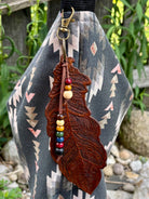 Close-up of hand-tooled leather feather texture and bronze swivel clasp