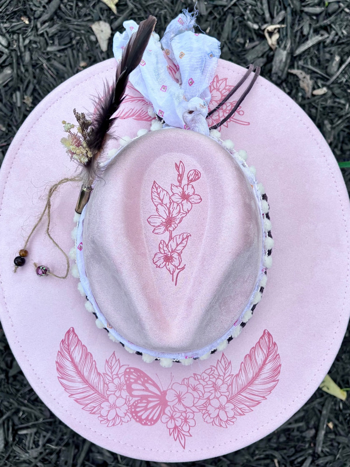 Close-up of hand-painted pink butterfly and feather design on rancher hat brim