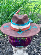 Bullet casing accent with feathers and dried florals on turquoise flower hat