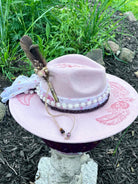 Bullet casing accent with feathers and dried florals on pink butterfly hat