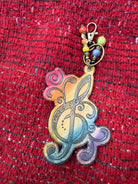 Hand-tooled leather treble clef bag charm in rainbow ombre, close up